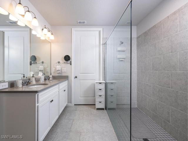 bathroom featuring double vanity, walk in shower, visible vents, and a sink