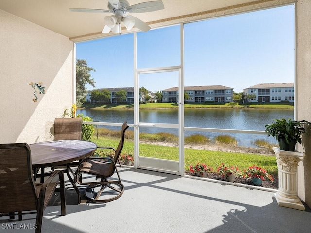 sunroom featuring a residential view, a water view, plenty of natural light, and a ceiling fan