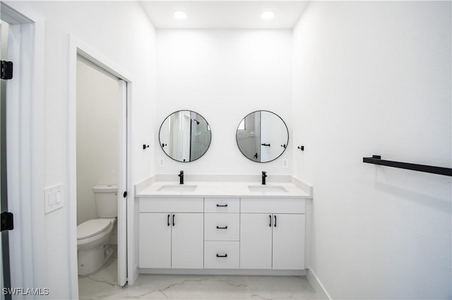 bathroom featuring double vanity, toilet, marble finish floor, and a sink