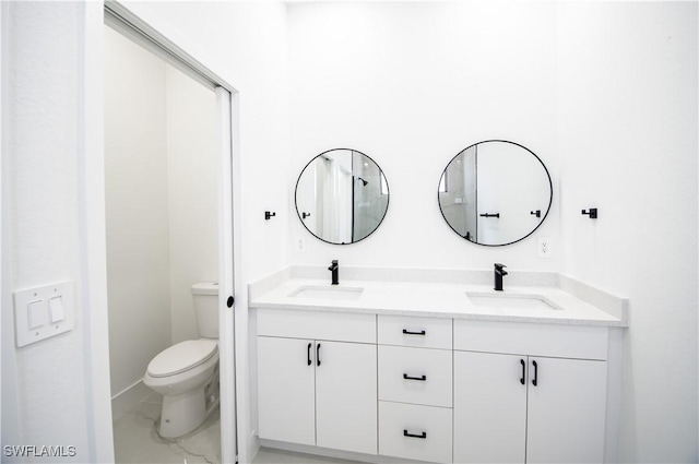 full bathroom with double vanity, toilet, marble finish floor, and a sink