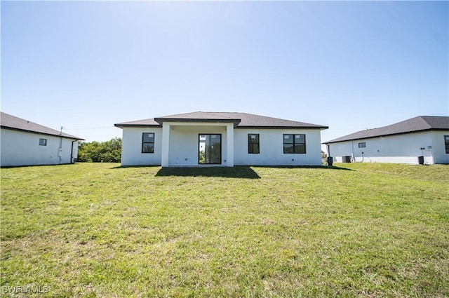 rear view of property featuring stucco siding and a lawn