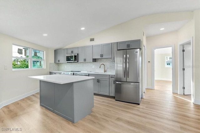 kitchen featuring a center island, a sink, stainless steel appliances, light countertops, and gray cabinetry