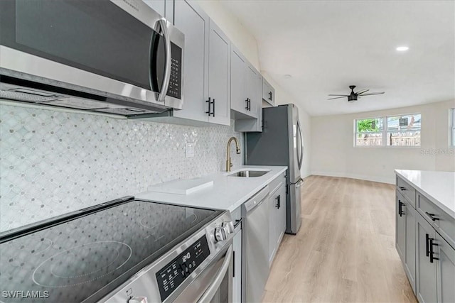 kitchen with light countertops, a ceiling fan, a sink, light wood-style floors, and appliances with stainless steel finishes