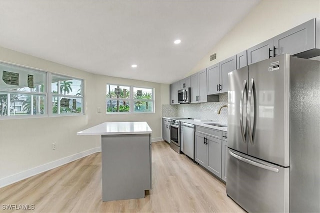 kitchen with stainless steel appliances, light countertops, gray cabinetry, and a sink