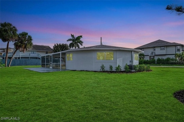rear view of property featuring fence, central air condition unit, stucco siding, a patio, and a lawn