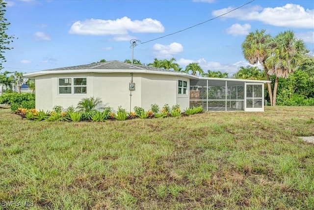 back of house featuring stucco siding, a sunroom, and a lawn