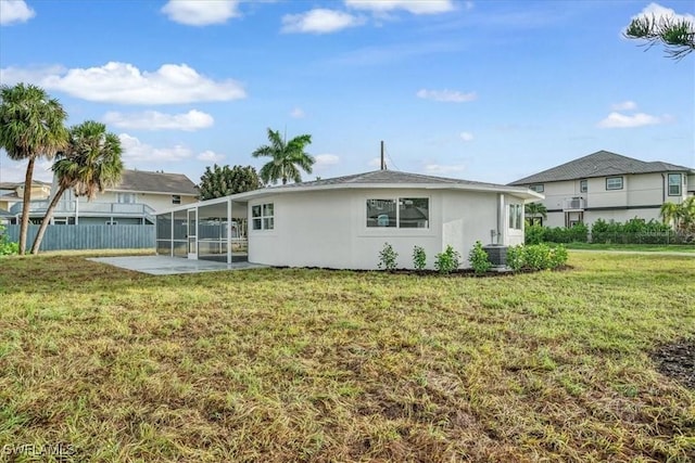 rear view of property featuring fence, stucco siding, a patio, a lawn, and a sunroom