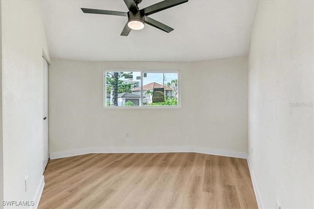 spare room featuring light wood-style floors, a ceiling fan, and baseboards
