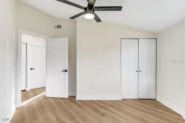 unfurnished bedroom featuring light wood finished floors, visible vents, a closet, and lofted ceiling