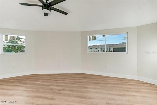 unfurnished room featuring a ceiling fan, baseboards, and light wood-style floors