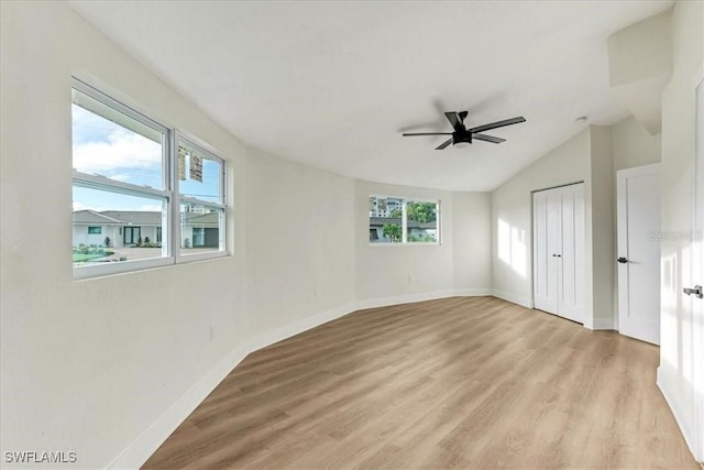 unfurnished bedroom with light wood-type flooring, baseboards, lofted ceiling, a closet, and ceiling fan