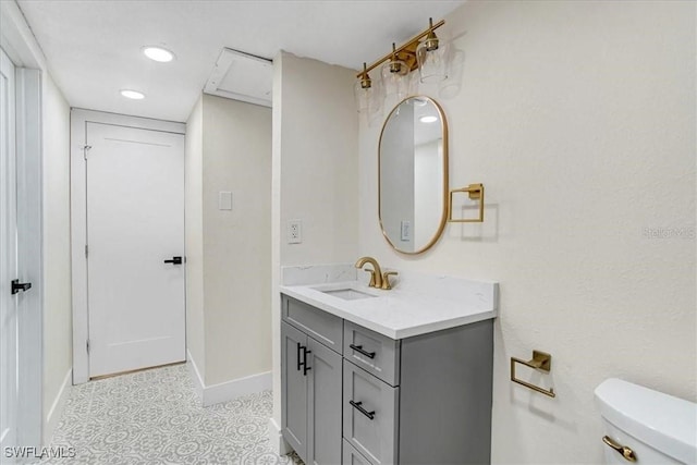 bathroom with baseboards, toilet, vanity, and recessed lighting
