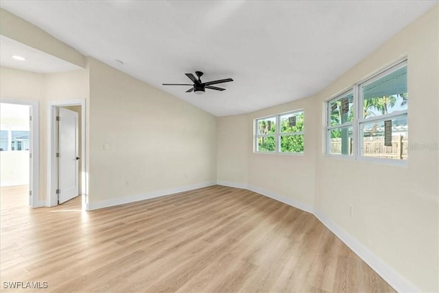 spare room with lofted ceiling, a ceiling fan, light wood finished floors, and baseboards