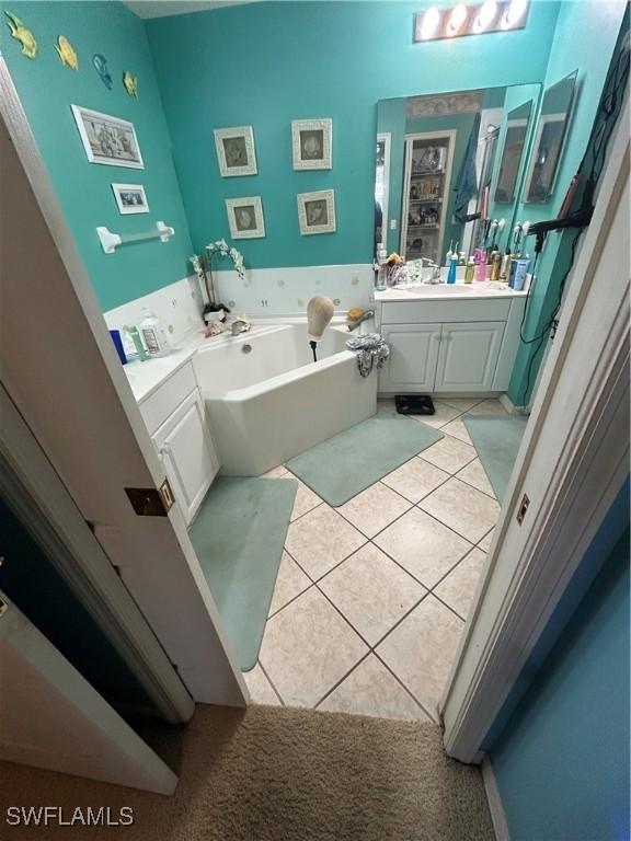 bathroom featuring tile patterned flooring, vanity, and a garden tub