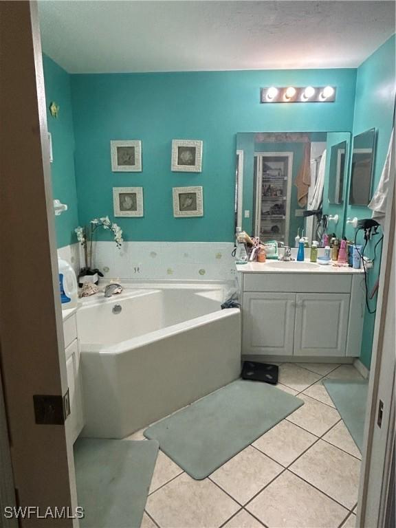 full bath with vanity, tile patterned floors, and a garden tub