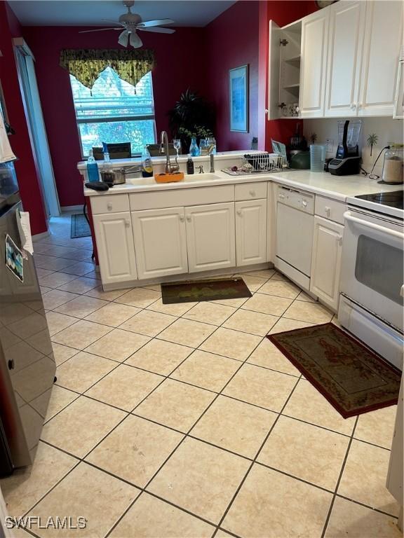 kitchen with light tile patterned flooring, white cabinets, white appliances, and a sink