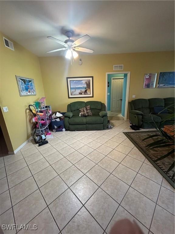 living area with light tile patterned floors, visible vents, baseboards, and a ceiling fan