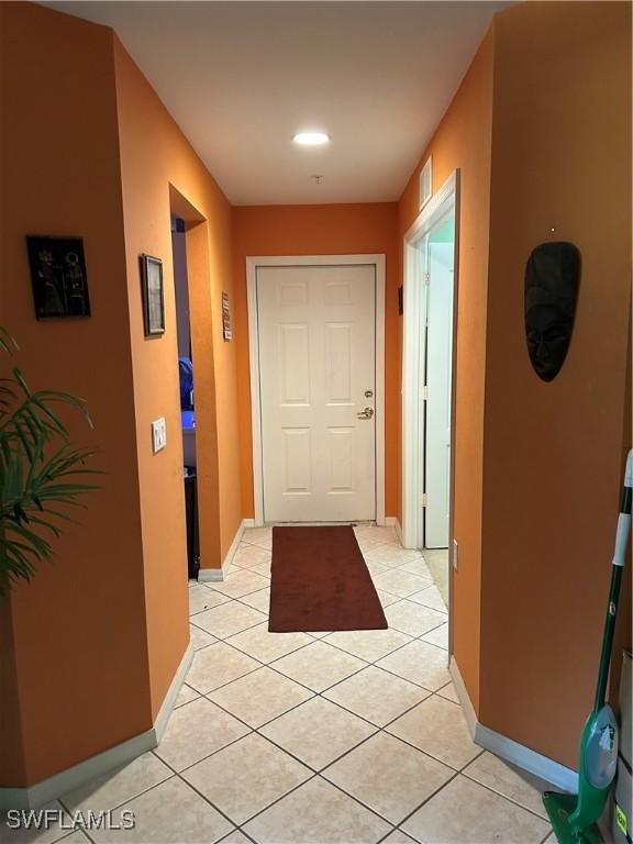 hall with light tile patterned flooring, visible vents, and baseboards