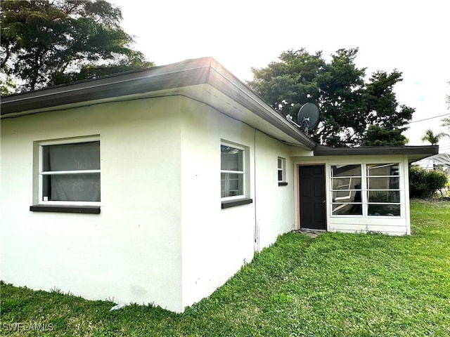 view of side of home with a yard and stucco siding