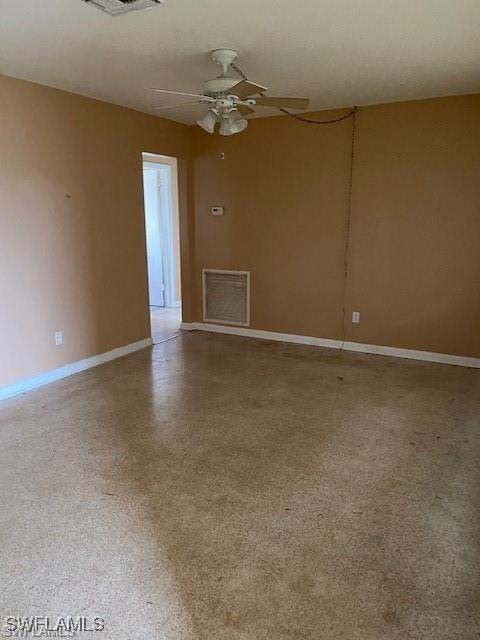 unfurnished room featuring baseboards, visible vents, and ceiling fan