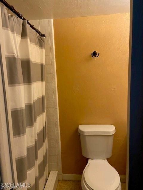 full bath featuring a shower with curtain, baseboards, and toilet