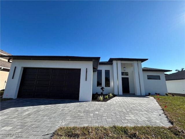 view of front of property featuring stucco siding, decorative driveway, and a garage