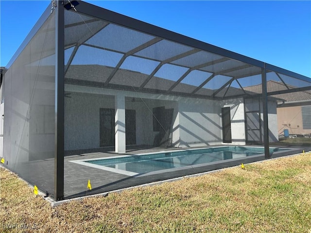 rear view of property featuring an outdoor pool, glass enclosure, and a patio area