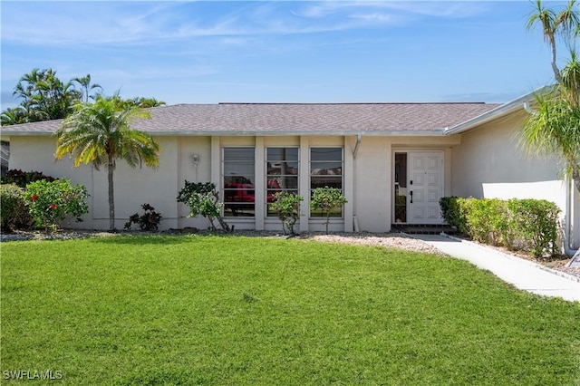 view of front of home featuring a front lawn, roof with shingles, and stucco siding