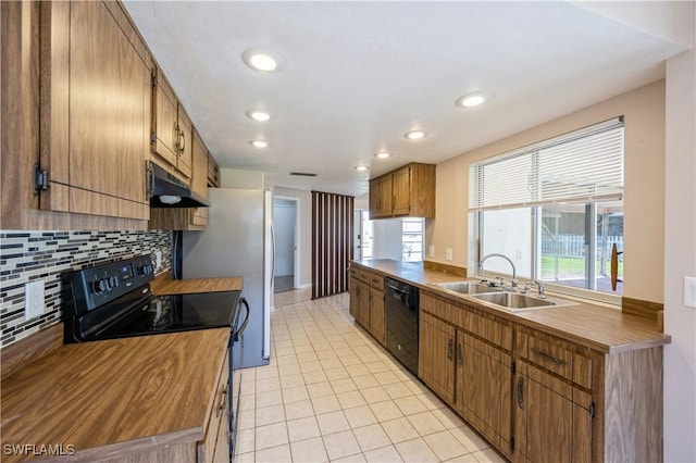 kitchen with black appliances, under cabinet range hood, a sink, light tile patterned floors, and decorative backsplash