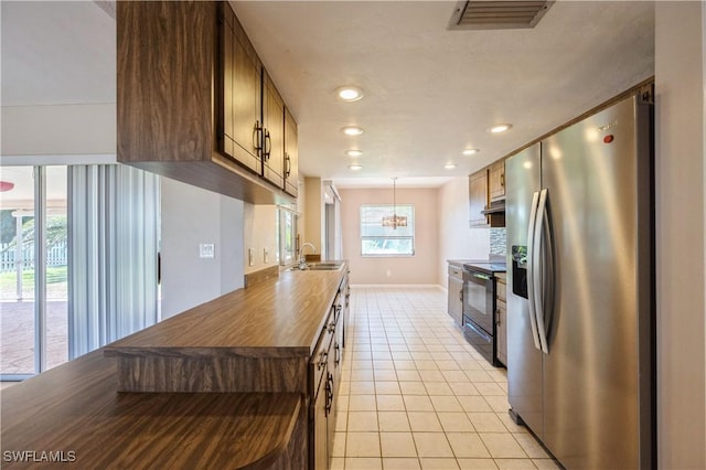 kitchen with visible vents, black range with electric stovetop, light tile patterned floors, stainless steel refrigerator with ice dispenser, and a sink