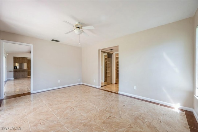 unfurnished room featuring visible vents, ceiling fan, and baseboards