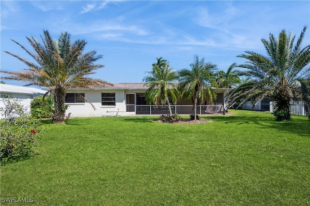 back of house with stucco siding, a lawn, fence, and a sunroom