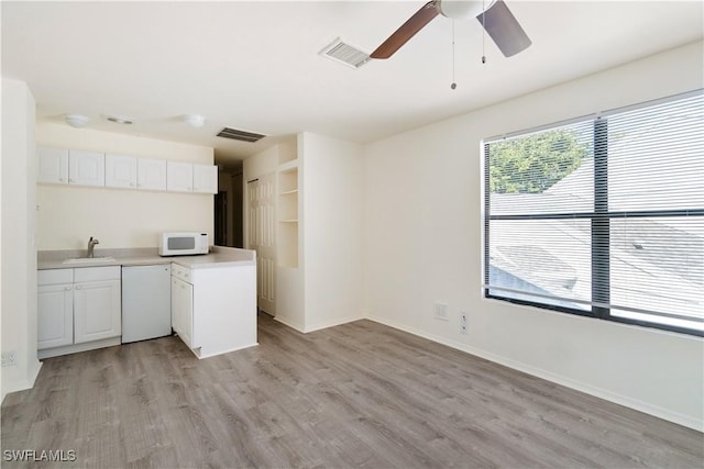 kitchen featuring white appliances, a ceiling fan, visible vents, a sink, and light countertops