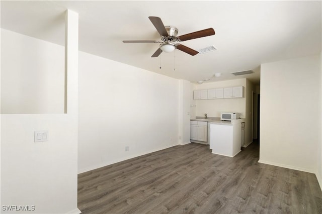 kitchen with a ceiling fan, dark wood-style floors, white microwave, visible vents, and white cabinets