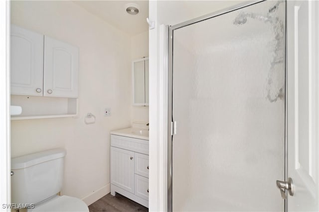 bathroom with vanity, wood finished floors, baseboards, a shower stall, and toilet