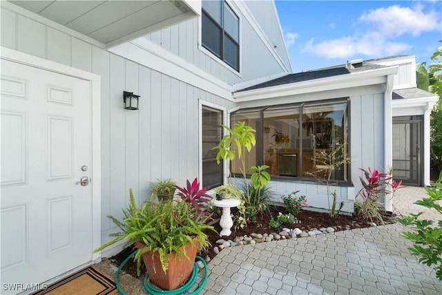 doorway to property with roof with shingles