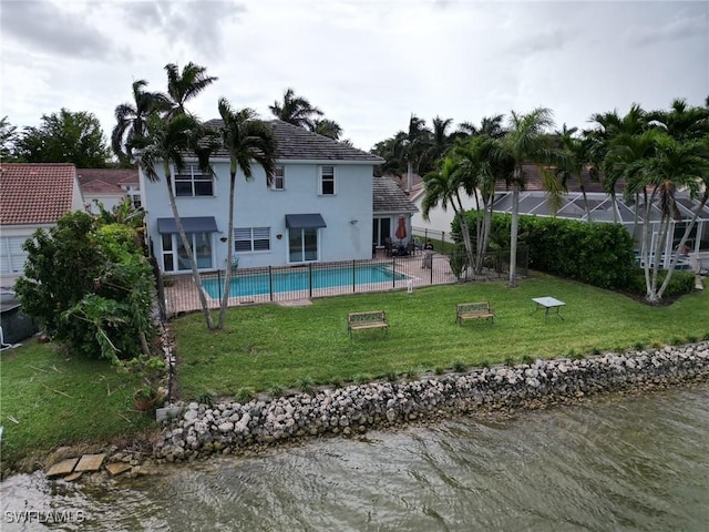 rear view of property with a yard, a water view, a fenced in pool, and stucco siding