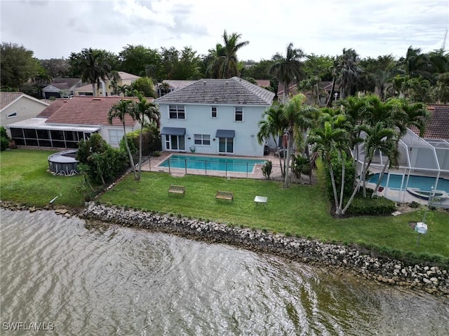 rear view of house featuring a lawn, an outdoor pool, and a water view