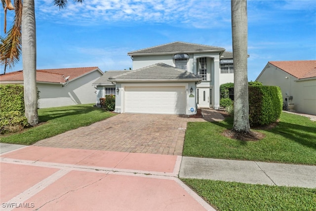 view of front of property with a front yard, decorative driveway, a garage, and stucco siding