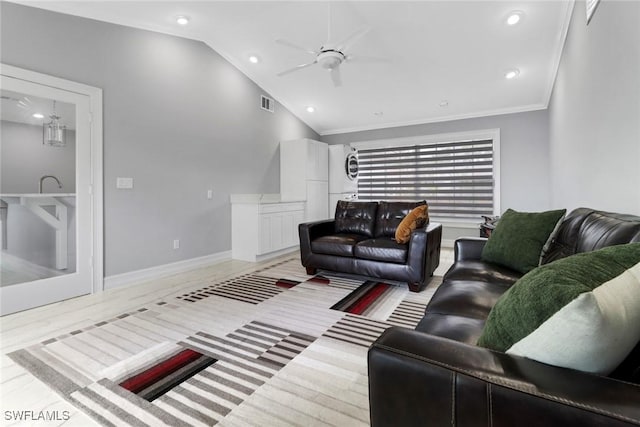 living room featuring baseboards, lofted ceiling, ornamental molding, ceiling fan, and stacked washer and dryer