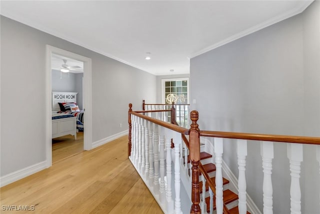 hallway with an upstairs landing, baseboards, light wood finished floors, and ornamental molding