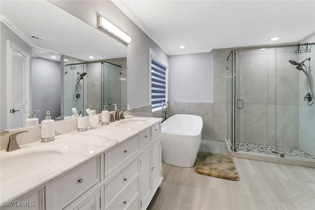 bathroom featuring a sink, a freestanding bath, a shower stall, and crown molding