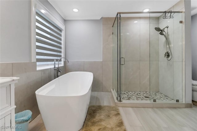 full bath with tile walls, a freestanding tub, toilet, and a stall shower