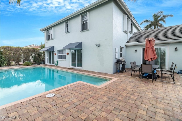 back of property featuring stucco siding, a patio, and a fenced in pool