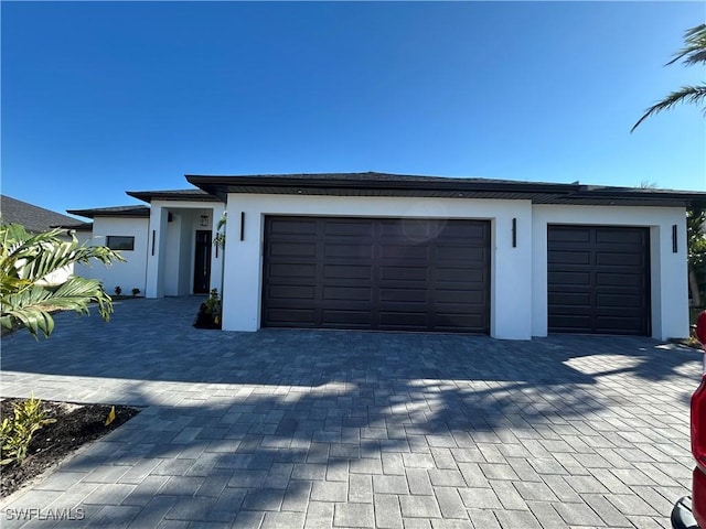 view of front facade featuring a garage, decorative driveway, and stucco siding