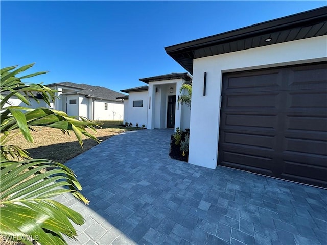 view of property exterior featuring decorative driveway, a garage, and stucco siding