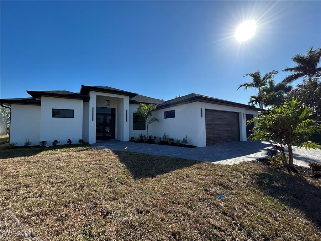 view of front of house with a front yard, an attached garage, driveway, and stucco siding