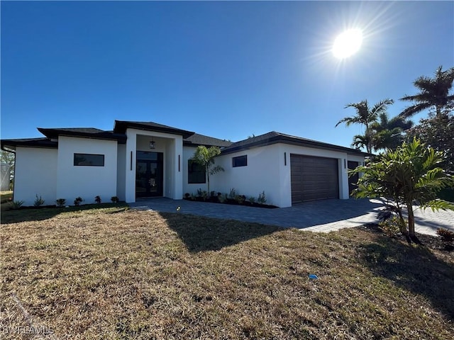 view of front of house with a front yard, an attached garage, driveway, and stucco siding