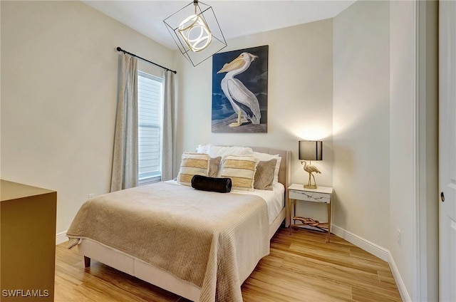 bedroom with a chandelier, baseboards, and wood finished floors