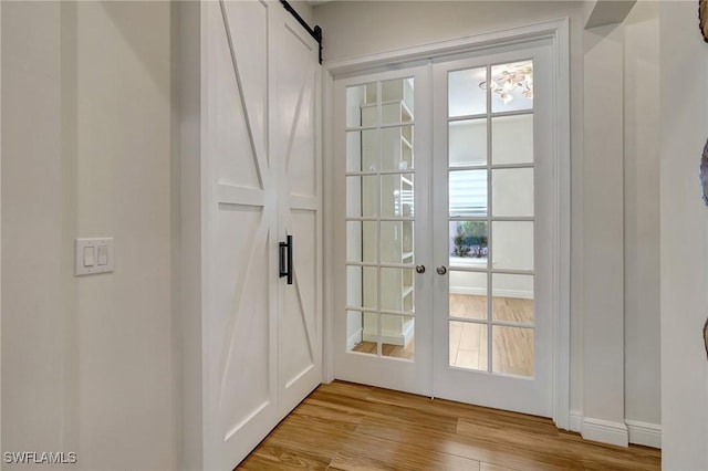 entryway featuring french doors, a barn door, and wood finished floors